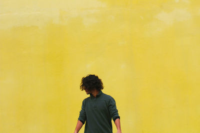 Man standing against yellow wall