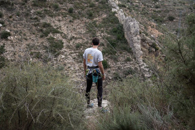 Rear view of man standing on cliff in forest