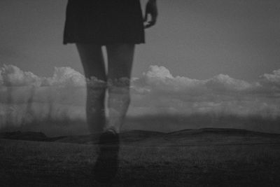 Low section of man standing on field against sky