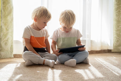 Brothers using digital tablet while sitting at home