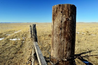 Wooden fence on field against clear sky