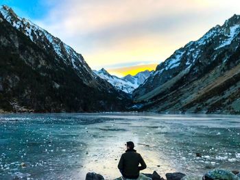 Rear view of person on snowcapped mountains against sky during winter