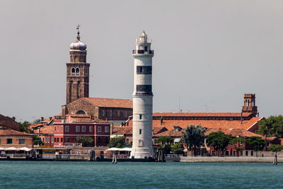 Tower by water in city against sky