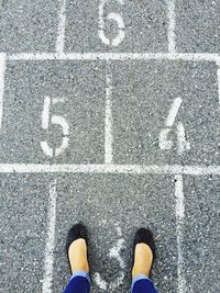 Low section of woman standing on hopscotch