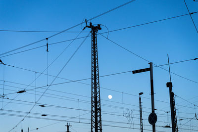 Low angle view of electricity pylon against blue sky