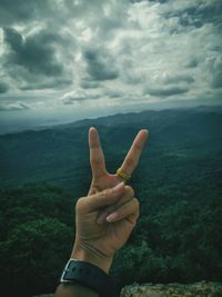 Cropped hand of woman gesturing against landscape