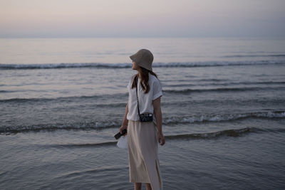 Rear view of woman standing at beach