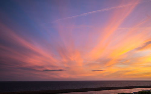 Scenic view of sea against dramatic sky during sunset