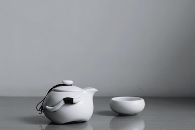 Tea kettle and bowl on table against wall