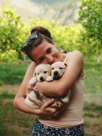 Portrait of woman holding puppies while standing at park