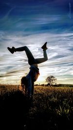 Silhouette girl doing handstand on field against sky during sunset