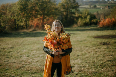 A woman holding branches during sunny autumn day