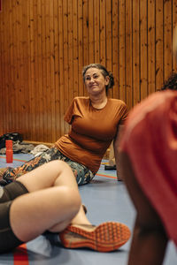 Smiling female athlete with disability sitting on floor at sports court