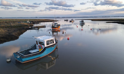 Fishing boats moored on sea against sky