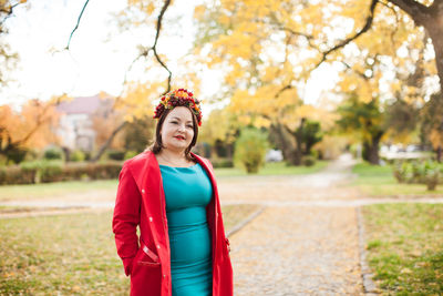 Portrait of smiling young woman standing in park during autumn