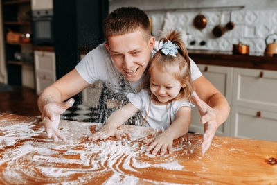 Funny happy dad and daughter baby cook together fool around and play with flour in  kitchen at home
