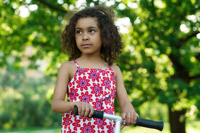 Portrait of young woman standing against trees