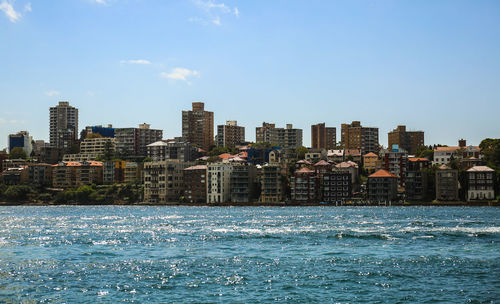 Sea by buildings against sky in city