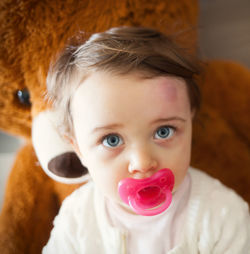 Close-up of cute girl with pacifier looking away at home