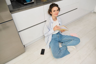 Portrait of young woman sitting on floor at home