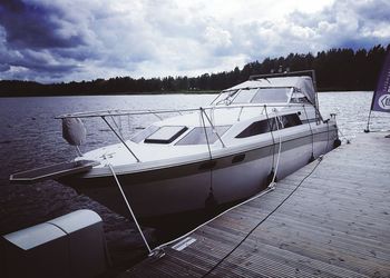 Boats in river against cloudy sky