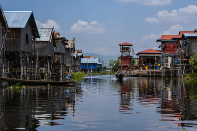 Buildings by river against sky in city