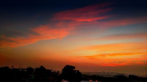 Silhouette trees against orange sky