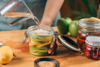 Close-up of hand holding glass jar on table