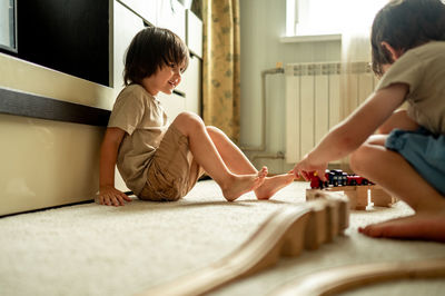 Two brothers play toys, they build a railway from a wooden construction set