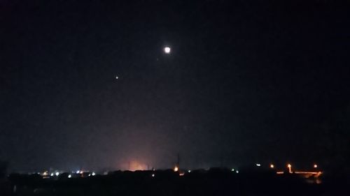 Low angle view of illuminated lights against sky at night