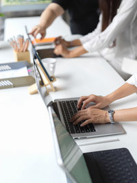Midsection of businesswomen using laptops on desk