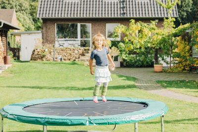 Full length portrait of girl jumping on trampoline outdoors