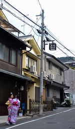 Rear view of woman walking on street amidst buildings in city