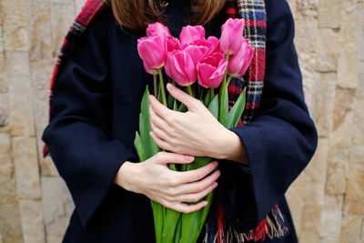 Young french millennial girl in beret and coat with tulips in hands