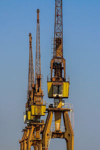 Low angle view of crane against clear blue sky