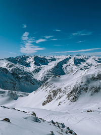 Scenic view of snow covered mountains against blue sky