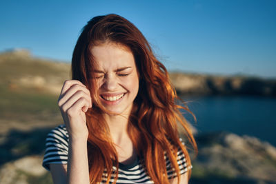 Portrait of smiling young woman against sky