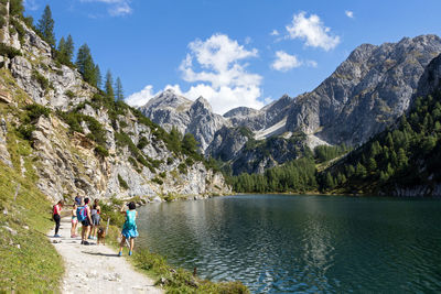 People walking on lake by mountains