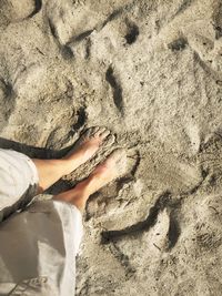 Low section of person standing on sand