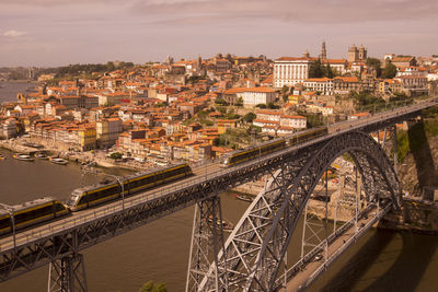 Trains on dom luis i bridge over douro river by city against sky