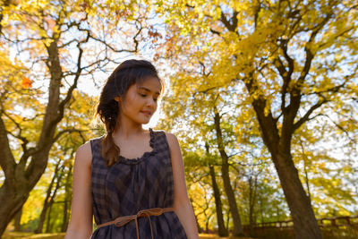 Low angle view of young woman standing against trees