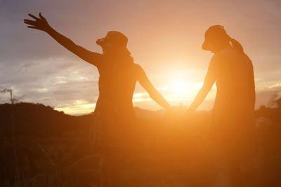 Silhouette couple standing against sun during sunset