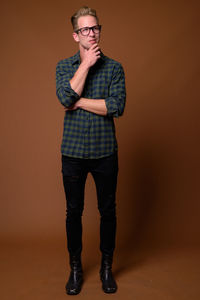 Full length portrait of young man standing against colored background