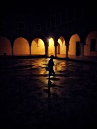 Silhouette of woman walking in illuminated building
