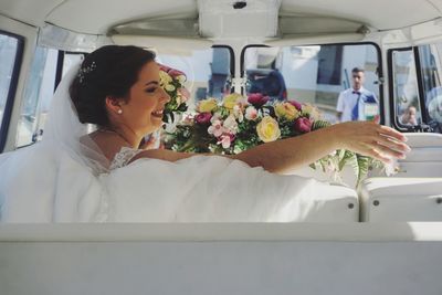 Rear view of bride gesturing while sitting in car