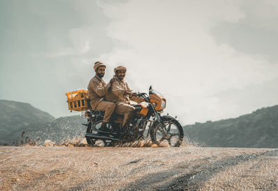 Man riding motorcycle on road against sky