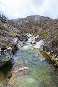 Scenic view of river flowing amidst mountains against sky