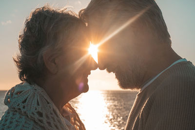 Senior couple embracing while standing against sea