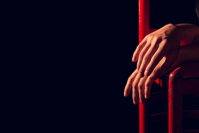 Close-up of woman hand on metal over black background