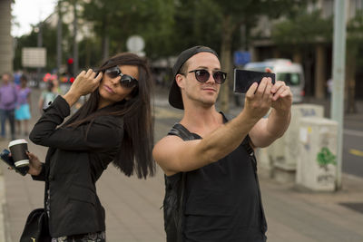 Young couple taking selfie on street through mobile phone